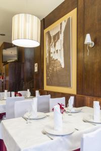 un comedor con mesas blancas y una foto en la pared en Hostal Restaurante Alarico, en Allariz