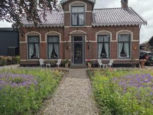a brick house with white chairs in front of it at B&B Klassiek in Twijzelerheide