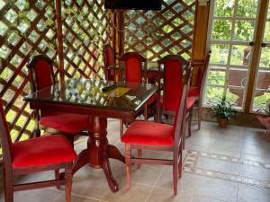 a dining room with a glass table and red chairs at Domacinstvo Ilici ,Gunjaci in Valjevo