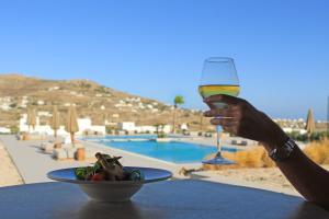 osoba trzymająca kieliszek wina obok talerza jedzenia w obiekcie Adama Mykonos Boutique Hotel w mieście Mykonos