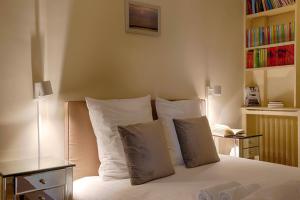 a bedroom with a bed with white sheets and pillows at La Villa Normande - One Bedroom in Deauville