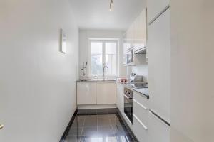 a white kitchen with white cabinets and a sink at La Villa Normande - One Bedroom in Deauville