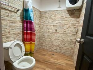 a bathroom with a toilet and a rainbow shower curtain at Hostal Mixteco Naba Nandoo in Oaxaca City