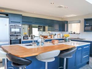 a kitchen with blue cabinets and a wooden counter top at Ferneytoun in Aboyne