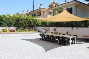 une table avec des chaises et une tente jaune sur une terrasse dans l'établissement Thalassa Casa Vacanza, à Anzio