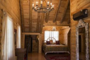 a bedroom in a log cabin with a bed and a chandelier at Log Country Inn Bed and Breakfast of Ithaca in Spencer