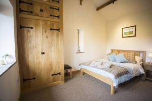 1 dormitorio con 1 cama y puerta de madera en Fuesli Lodge - Boutique Cottage at Harrys Cottages en Pen y Clawdd
