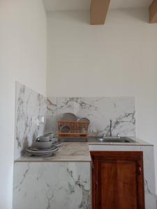 uma cozinha com paredes de mármore branco e um lavatório em Hotel y Plaza JMI em Siguatepeque