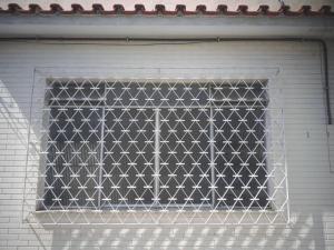 Apartamento(1) inteiro com sala reversivel في فولتا ريدوندا: نافذة على باب المرآب الأبيض مع شبك معدني