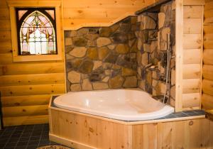 a bath tub in a room with a stone wall at Log Country Inn Bed and Breakfast of Ithaca in Spencer