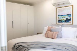 a bedroom with a bed with white cabinets and a painting at Port Lincoln Beachfront Apartment 7 in Port Lincoln