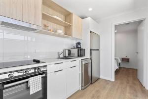a kitchen with white cabinets and a stainless steel refrigerator at Port Lincoln Beachfront Apartment 7 in Port Lincoln