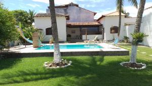 a house with a swimming pool and two palm trees at Suite Aconchegante 01 in Saquarema