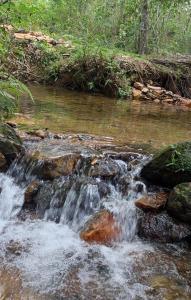 una corriente de agua corriendo sobre las rocas en un río en Camping Nhá Chica, en São Thomé das Letras