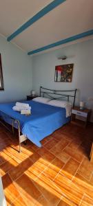 una camera da letto con un letto blu e un pavimento in legno di Sa Domu Tabarchina a Calasetta