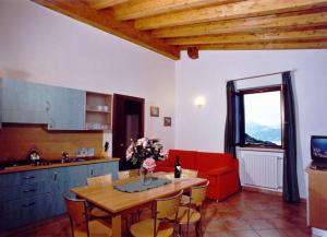 een keuken en eetkamer met een tafel en een rode bank bij Residence Garden in Tignale