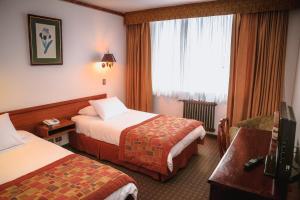 Habitación de hotel con 2 camas y ventana en HOTEL LOS NAVEGANTES, en Punta Arenas