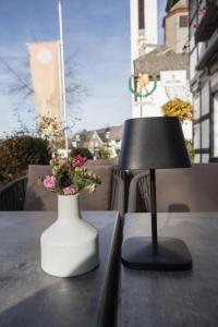 a lamp and a vase with flowers on a table at Boutique-Hotel Weigels Bergfreiheit in Winterberg
