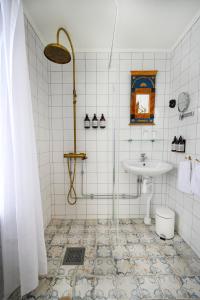 uma casa de banho em azulejos brancos com um lavatório e um chuveiro em Ölme Prästgård Gästgiveri em Kristinehamn