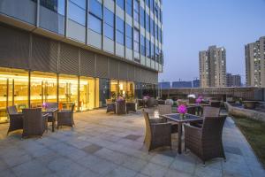 a patio with tables and chairs in front of a building at Citadines Intime City Hangzhou in Hangzhou