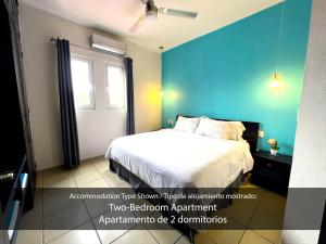 a bedroom with a bed and a blue wall at Cárdenas Suites in Puerto Vallarta