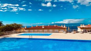 una gran piscina frente a una casa en OZEAN SUNSET HOUSE, en Puerto de Santiago