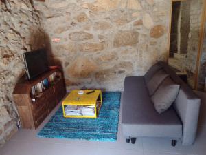 ein Wohnzimmer mit einem Sofa, einem TV und einem Tisch in der Unterkunft Moinho do ribeirinho, renovado vintage in Campos de Sá