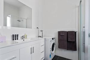 a white bathroom with a washing machine and a sink at Port Lincoln Shark Apartment 4 in Port Lincoln