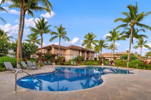 una piscina con palmeras frente a una casa en Big Island Waikoloa Colony Villas condo, en Waikoloa