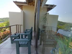 a balcony with chairs and tables on a house at Ekuthuleni Modern Christian Guesthouse with seaview in Umhlanga Ridge