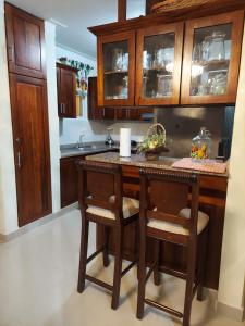 eine Küche mit Holzschränken und einer Theke mit Stühlen in der Unterkunft Jardines de tu sueño. in Santiago de los Caballeros