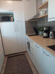 uma cozinha com armários brancos e um frigorífico branco em Ihastuttava kaksio Pieksämäen keskustasta em Pieksamaki