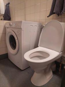 a bathroom with a toilet and a washing machine at Kodikas kaksio Pieksämäen keskustasta in Pieksamaki +9 photos