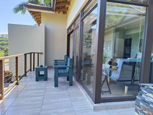 a balcony with glass doors and a table and chairs at Ekuthuleni Modern Christian Guesthouse with seaview in Umhlanga Ridge