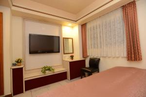 a hotel room with a bed, television and a desk at Hua Guo Hotel in Keelung