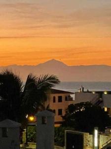 una puesta de sol sobre una ciudad con un edificio y palmeras en Villa Garoe, en Puerto de las Nieves