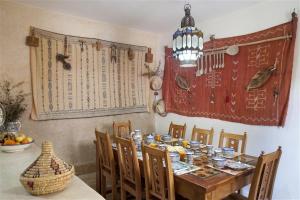 a dining room with a table with chairs and a chandelier at Dar KamalChaoui in Bhalil