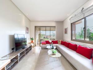 ein Wohnzimmer mit einem roten Sofa und einem Flachbild-TV in der Unterkunft Les Jardins Du Paradis 3 chambres avec golf et parking gratuit in Marrakesch