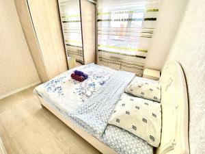 ein kleines Bett in einem Zimmer mit Fenster in der Unterkunft Апартаменты 2 комнатная в новом ЖК in Aqtöbe