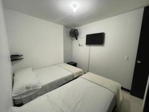 Habitación pequeña con 2 camas y TV. en Edificio guaduales del cafe 505A, en Montenegro