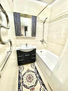 La salle de bains est pourvue d'un lavabo, d'une baignoire et d'un miroir. dans l'établissement Апартаменты 2 комнатная в новом ЖК, à Aqtöbe