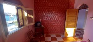 um quarto com uma janela e uma televisão numa parede em Gasser Holiday Home em Aswan
