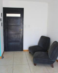 a living room with a black door and a chair at CN departamentos in Guaymallen
