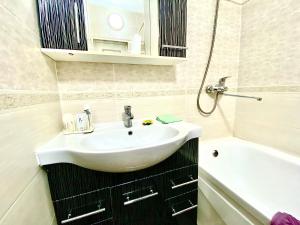 ein Badezimmer mit einem weißen Waschbecken und einer Badewanne in der Unterkunft Апартаменты 2 комнатная в новом ЖК in Aqtöbe