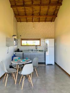 kuchnia ze stołem, krzesłami i lodówką w obiekcie Via Del Mare Flats w mieście Maraú