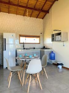 cocina con mesa, sillas y nevera en Via Del Mare Flats, en Maraú