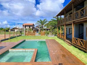 un patio trasero con piscina y una casa en Via Del Mare Flats, en Maraú