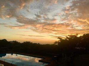 a sunset over a swimming pool with the sun setting at V's studio in Ballito