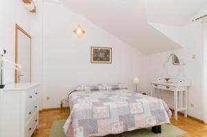 a white bedroom with a bed and a white desk at Apartment and Rooms Mate in Bol