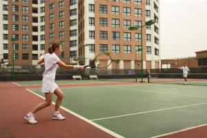 a woman playing tennis on a tennis court at Somerset Grand Hanoi in Hanoi